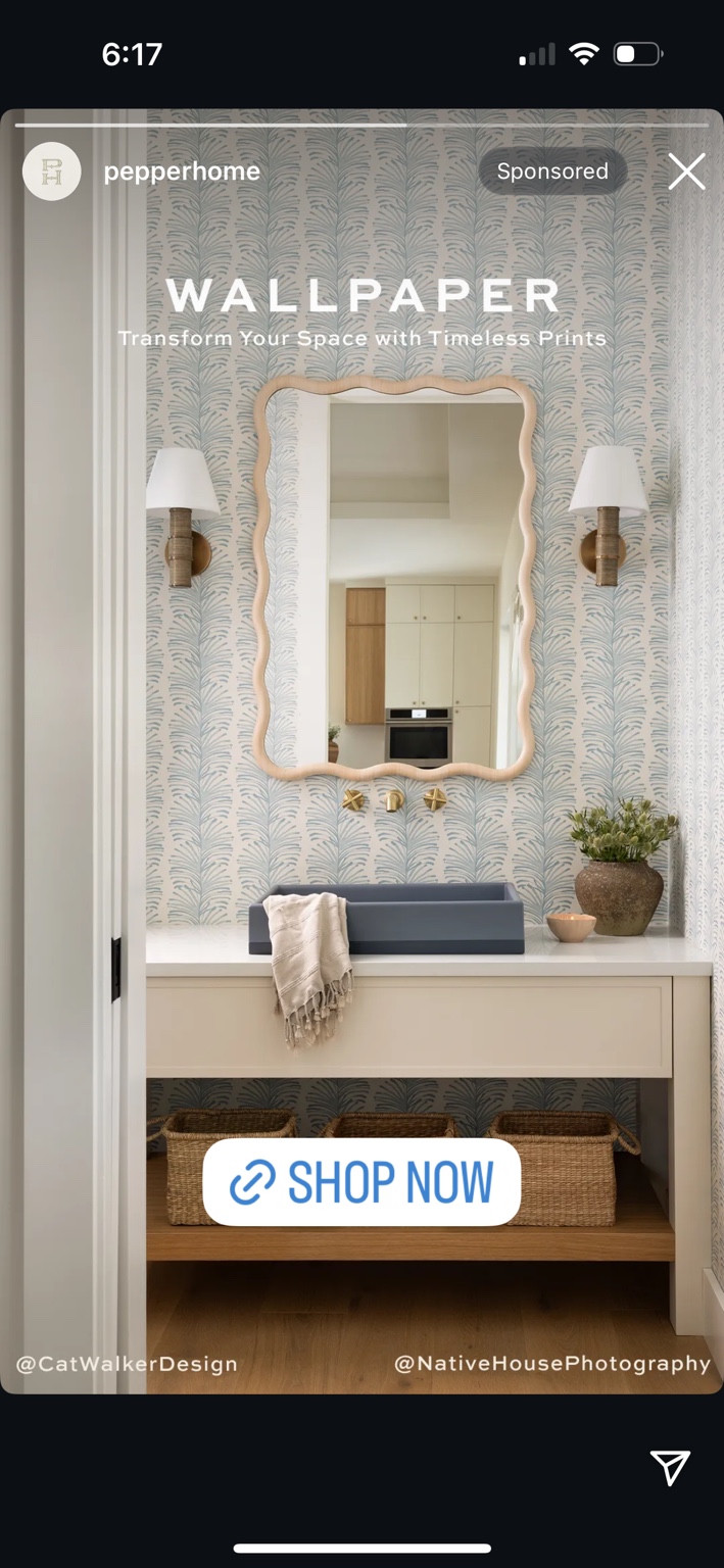 Bathroom inspiration with blue botanical wallpaper, a scalloped mirror and wall sconces.
